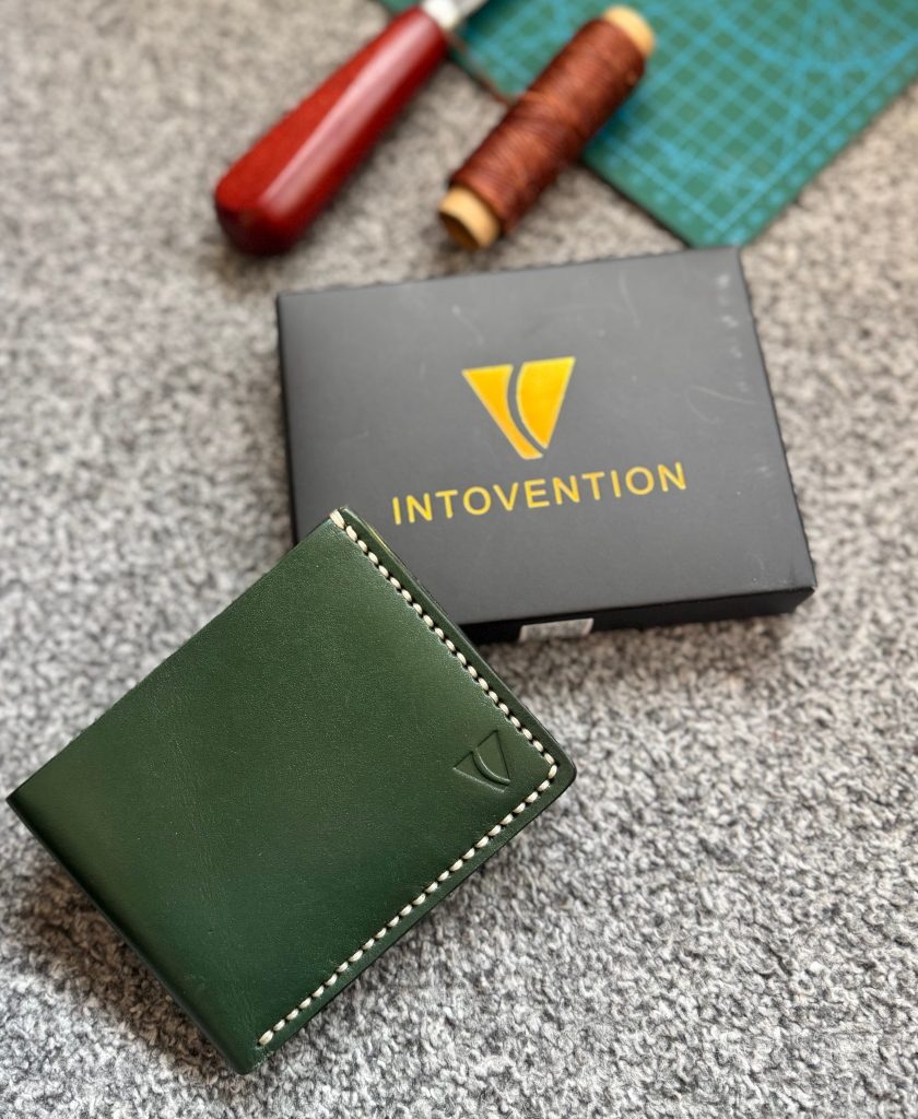 Forest green Intovention leather wallet with branded box and craft tools